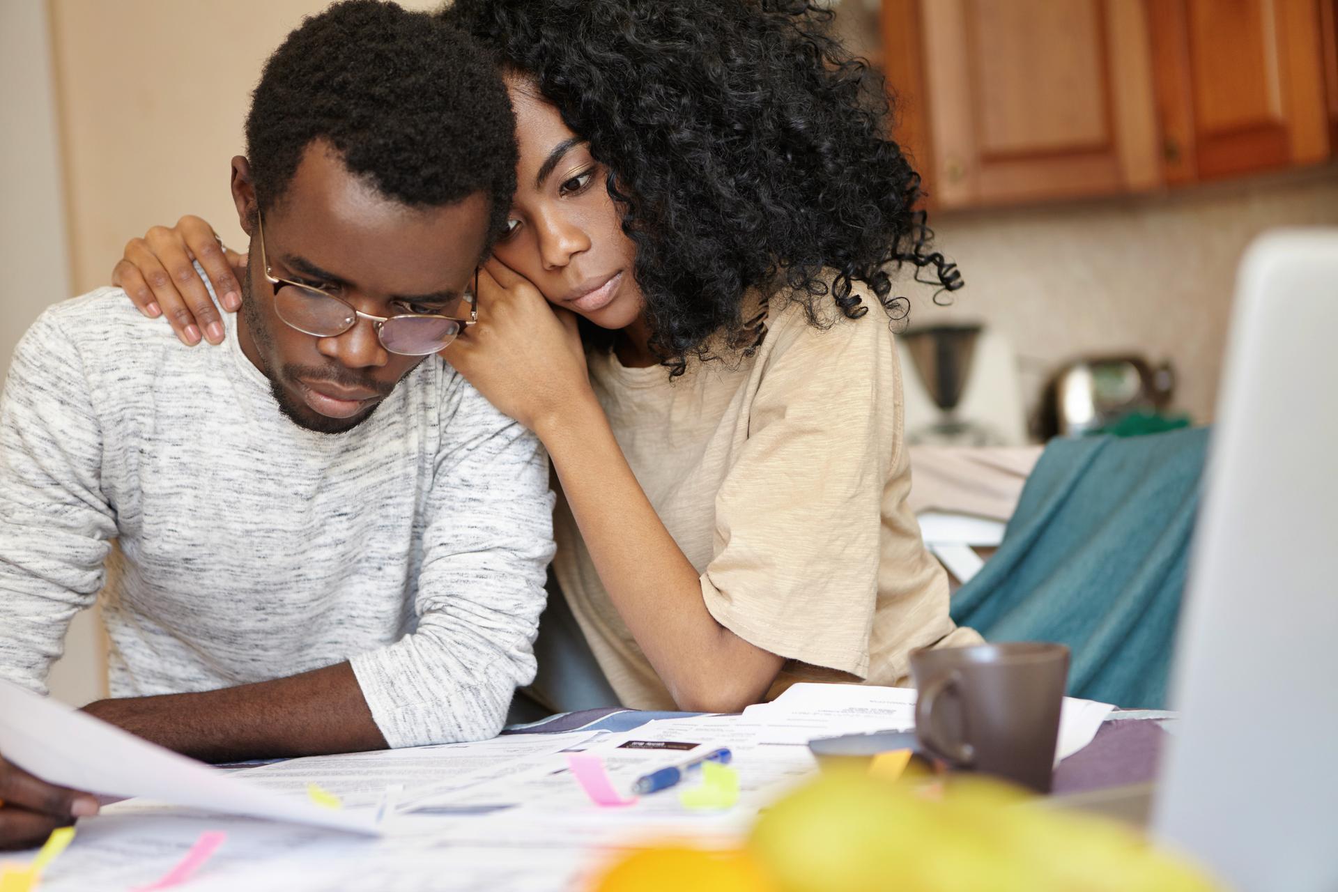 Couple stressed reviewing bills at kitchen table